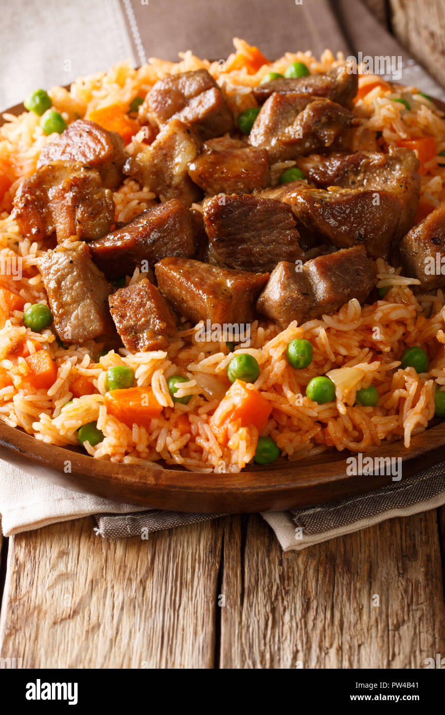 Delicious Mexican rice with vegetables served with spicy pork close-up on a plate on the table. vertical Stock Photo