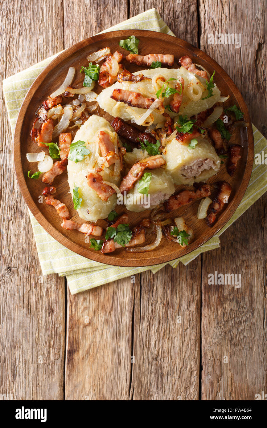 Cepelinai zeppelins or didzkukuliai is a traditional Lithuanian dish of stuffed potato dumplings close-up on table. Vertical top view from above Stock Photo