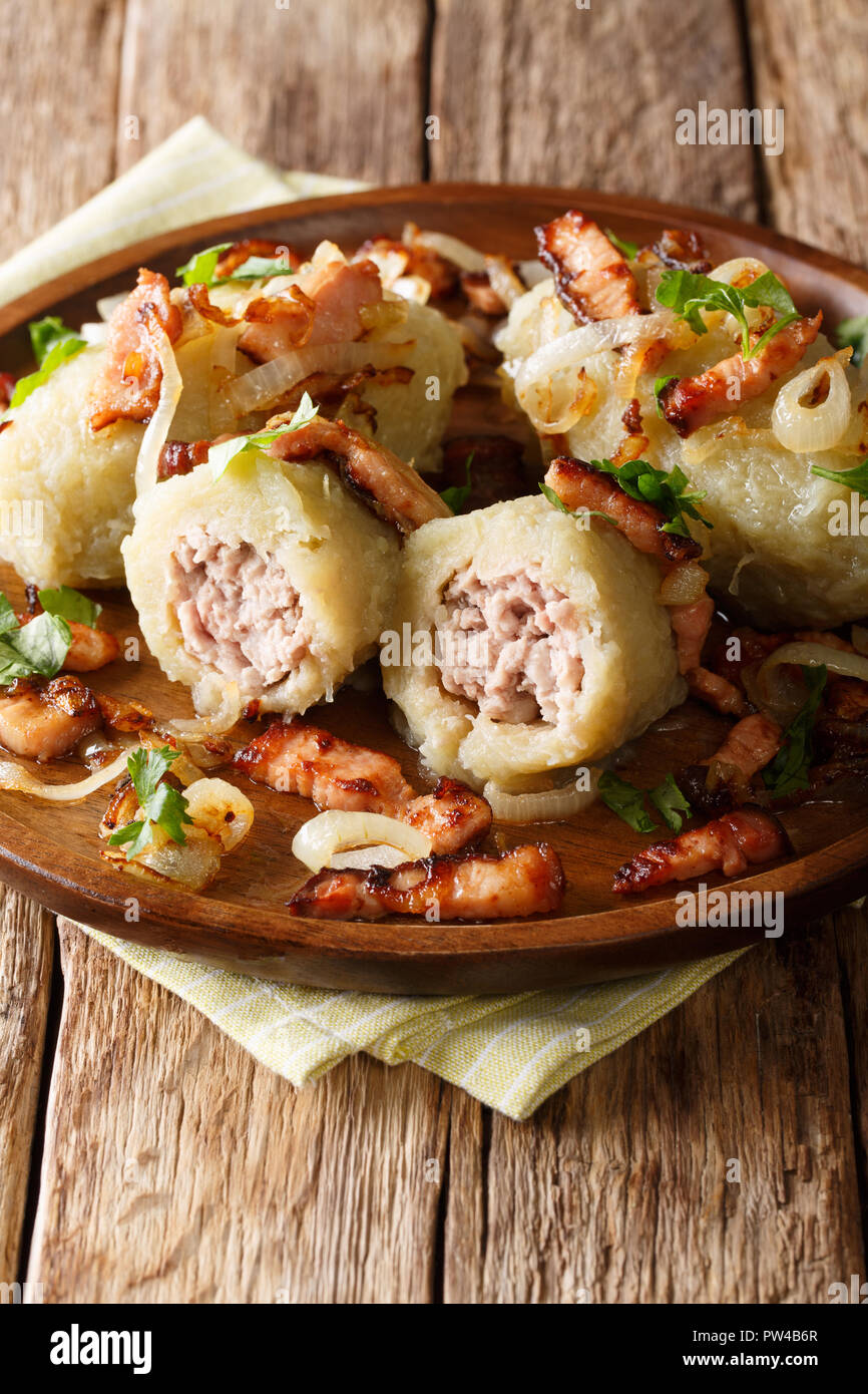 Cepelinai zeppelins or didzkukuliai is a traditional Lithuanian dish of stuffed potato dumplings close-up on table. vertical Stock Photo