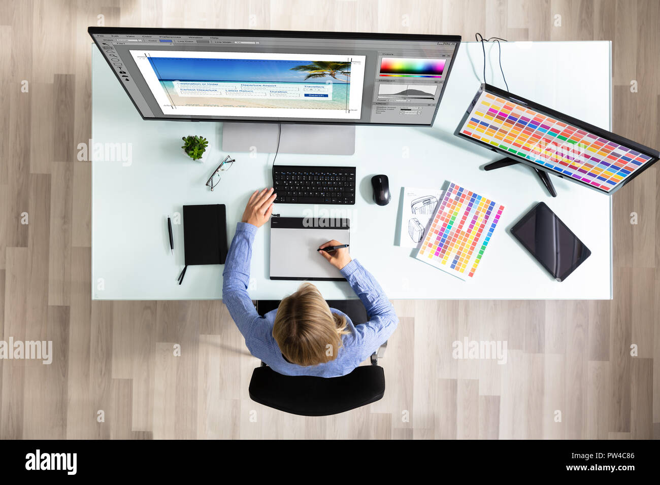 Elevated View Of Female Editor Using Graphic Tablet While Working On Computer In Office Stock Photo