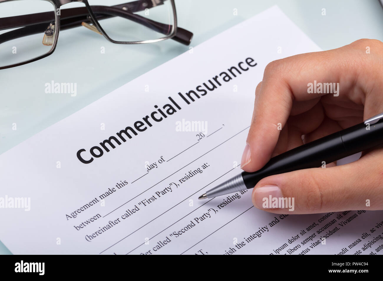 Close-up Of A Person's Hand Filling Commercial Insurance Form Stock Photo