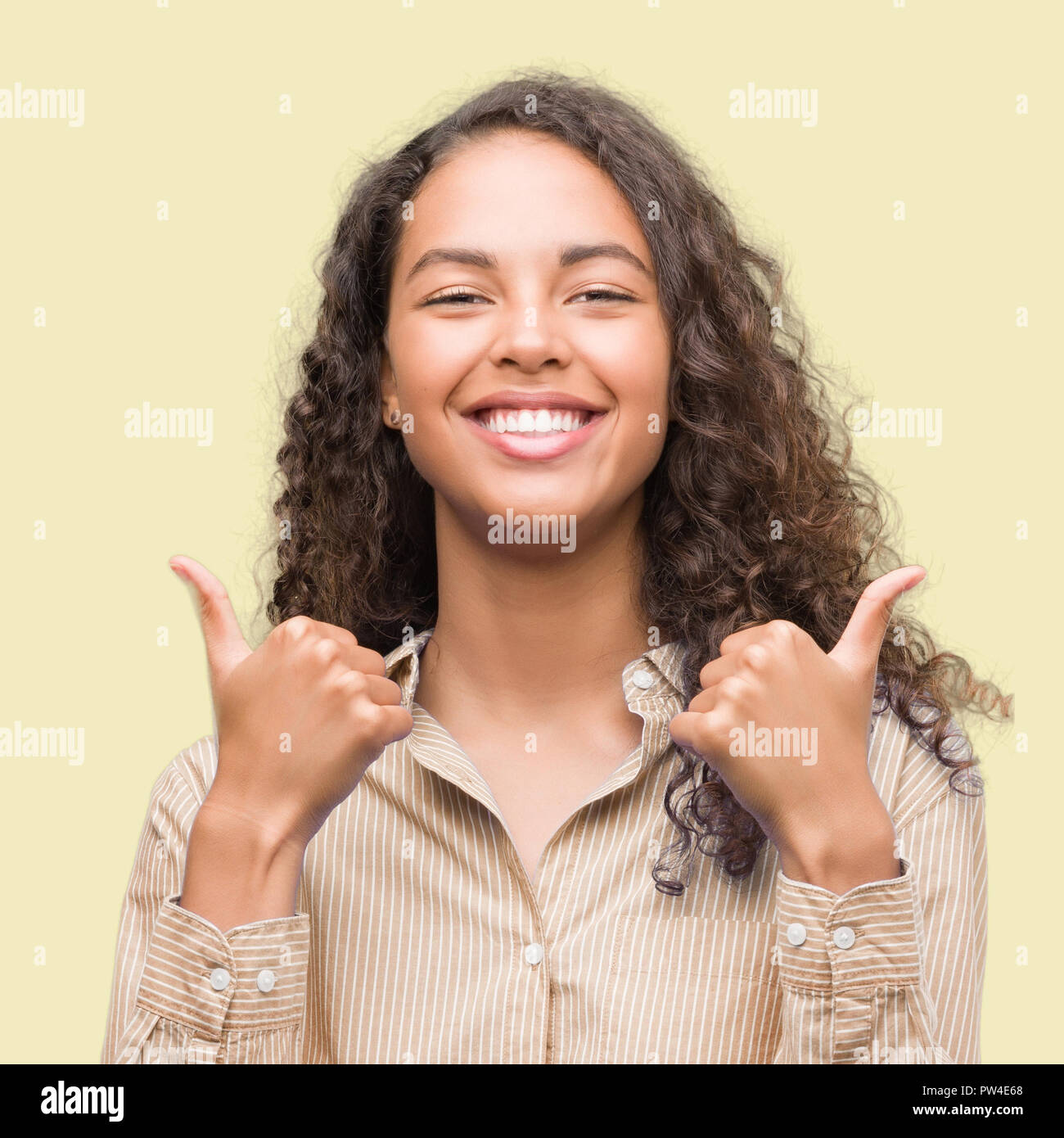Young hispanic business woman success sign doing positive gesture with ...