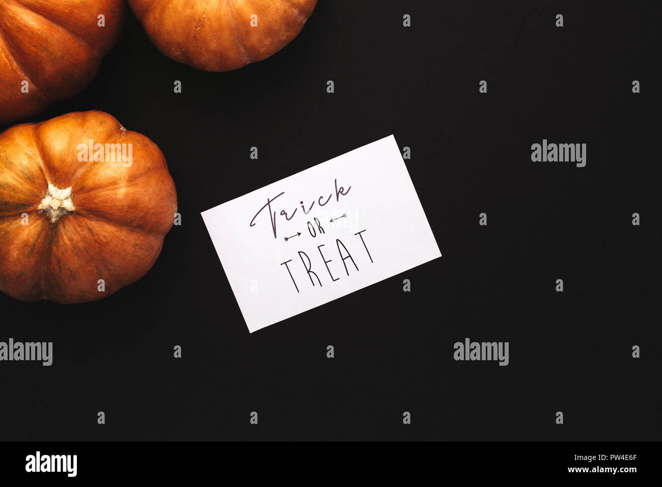 Top view of pumpkins with trick or treat card on black background. Halloween flat lay. Stock Photo