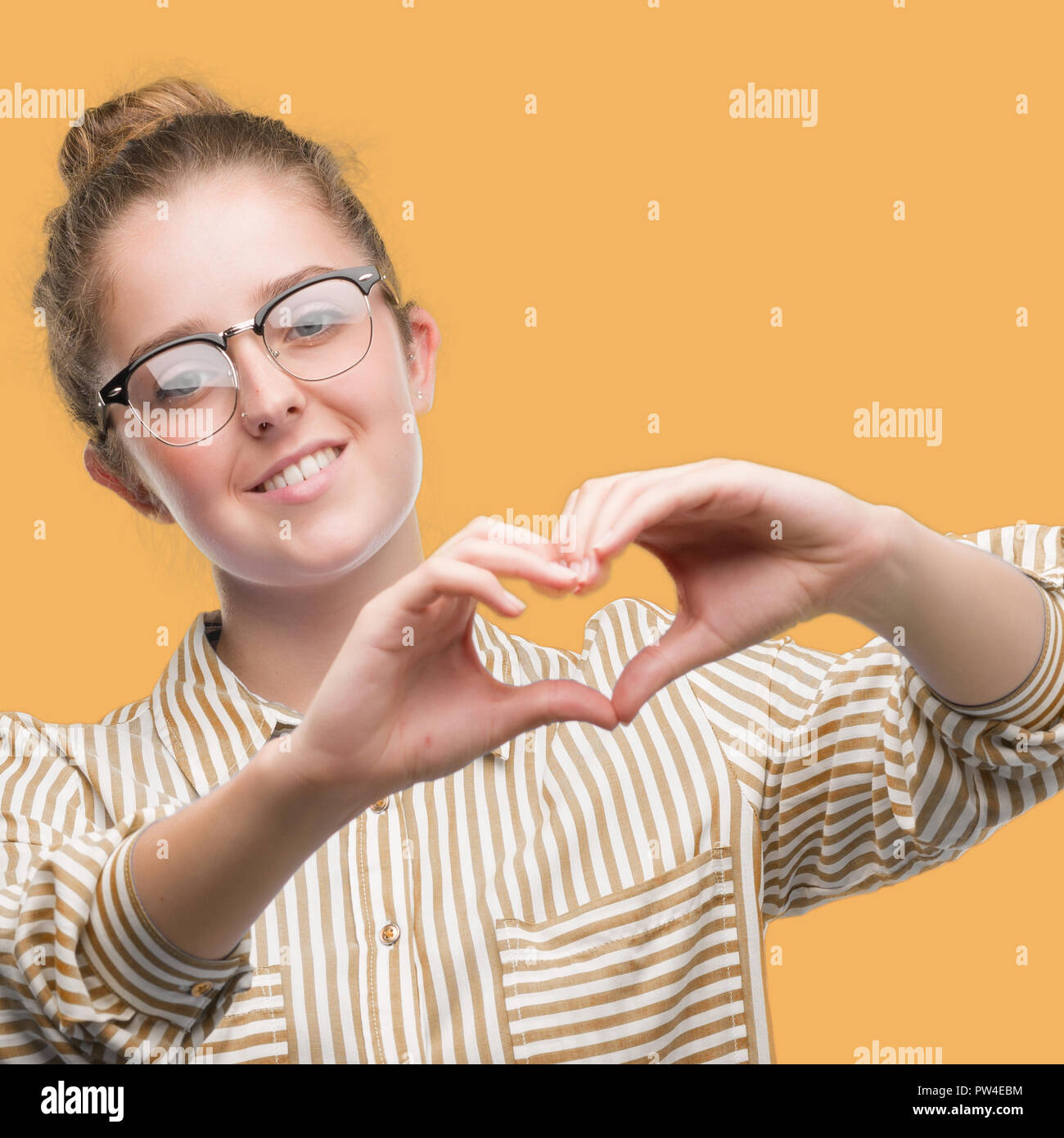 Young blonde business woman smiling in love showing heart symbol and ...