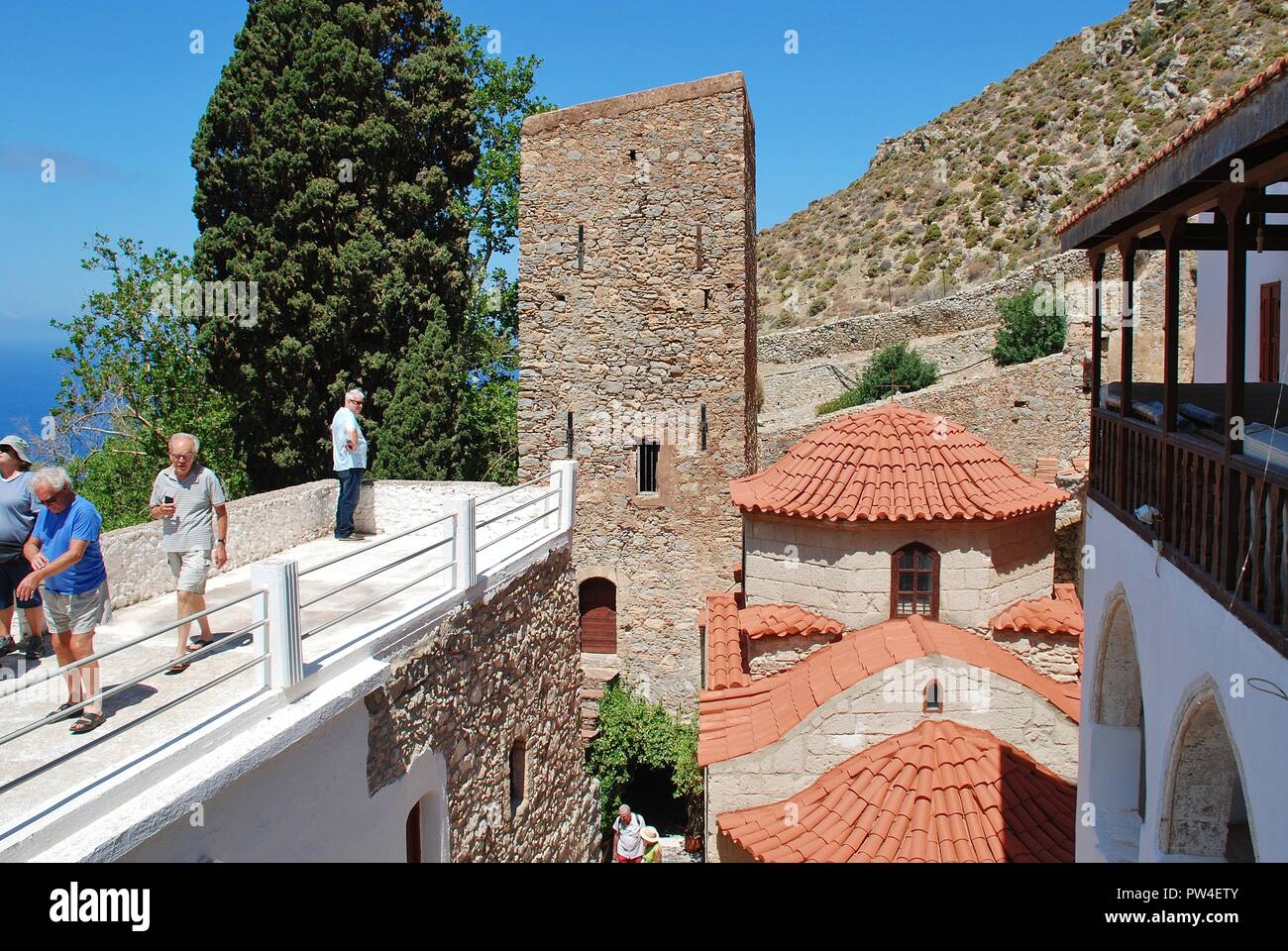 Tourists walk around the Byzantine period monastery of Agios Panteleimon on the Greek island of Tilos. The monastery dates from around 1470. Stock Photo