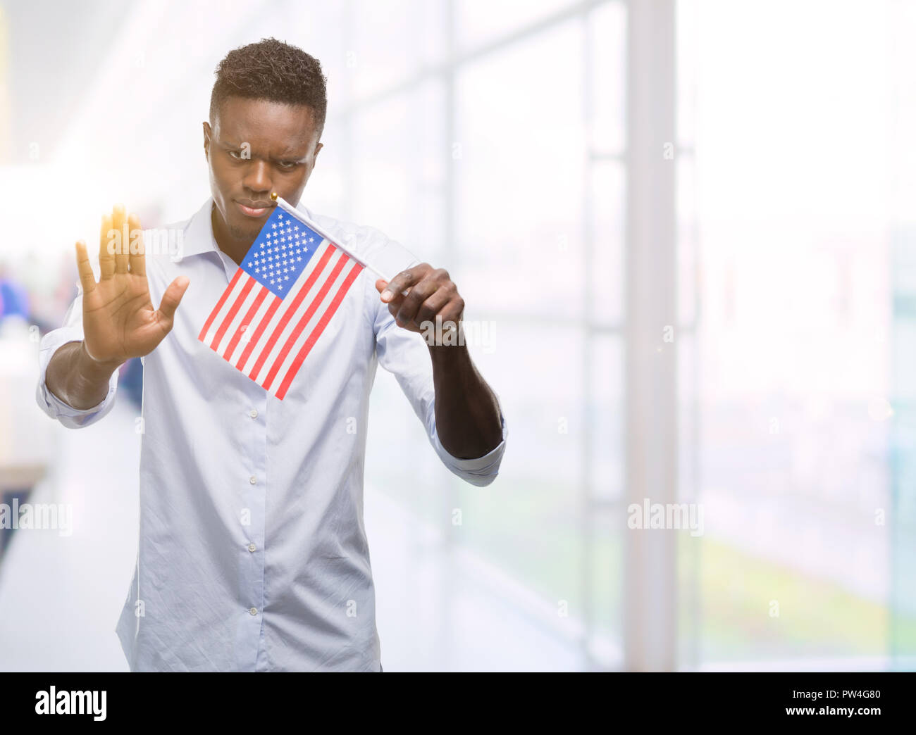 Young african american man holding USA flag with open hand doing stop ...