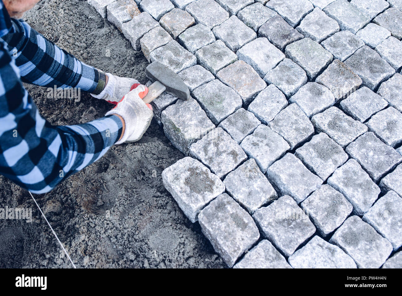 industrial worker installing pavement rocks, cobblestone blocks on road ...