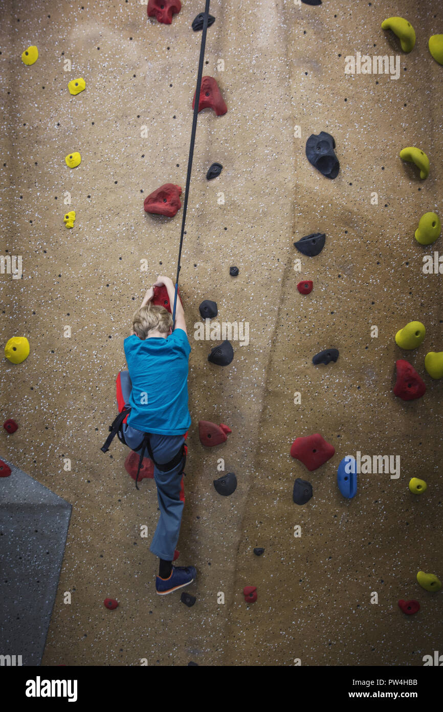 Rear view of boy climbing wall in health club Stock Photo
