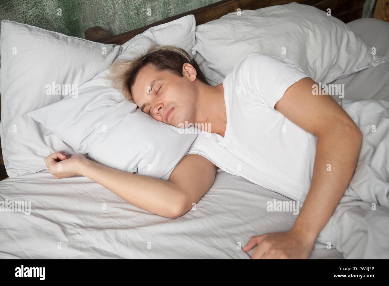 Young male lying in bed and sleeping Stock Photo