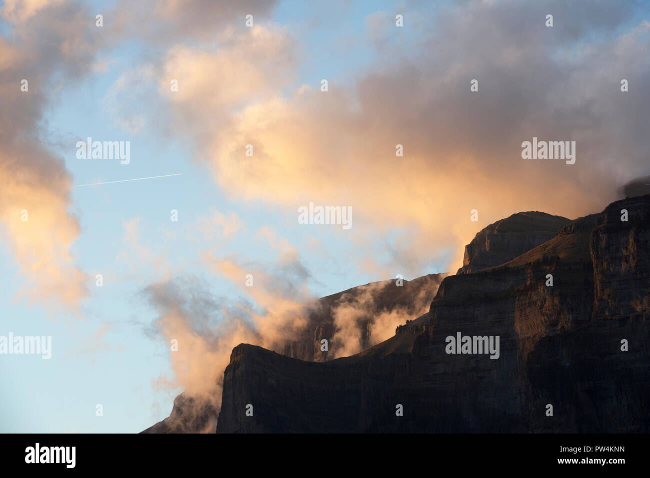 Low angle view of silhouette mountains against cloudy sky during sunset at Ordesa y Monte Perdido National Park Stock Photo
