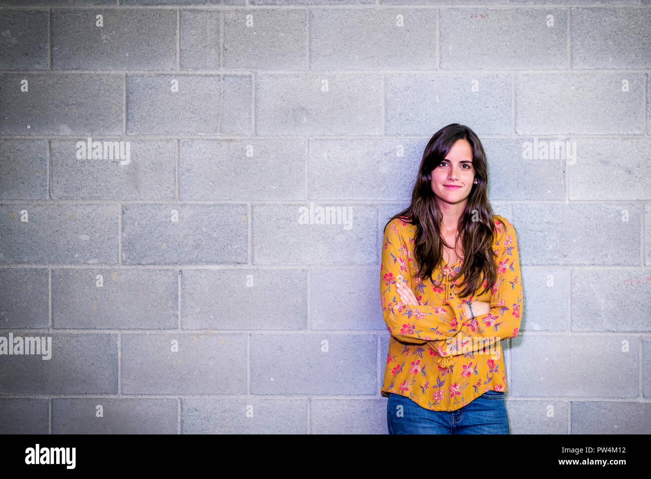 Portrait of confident businesswoman with arms crossed standing against wall in office Stock Photo