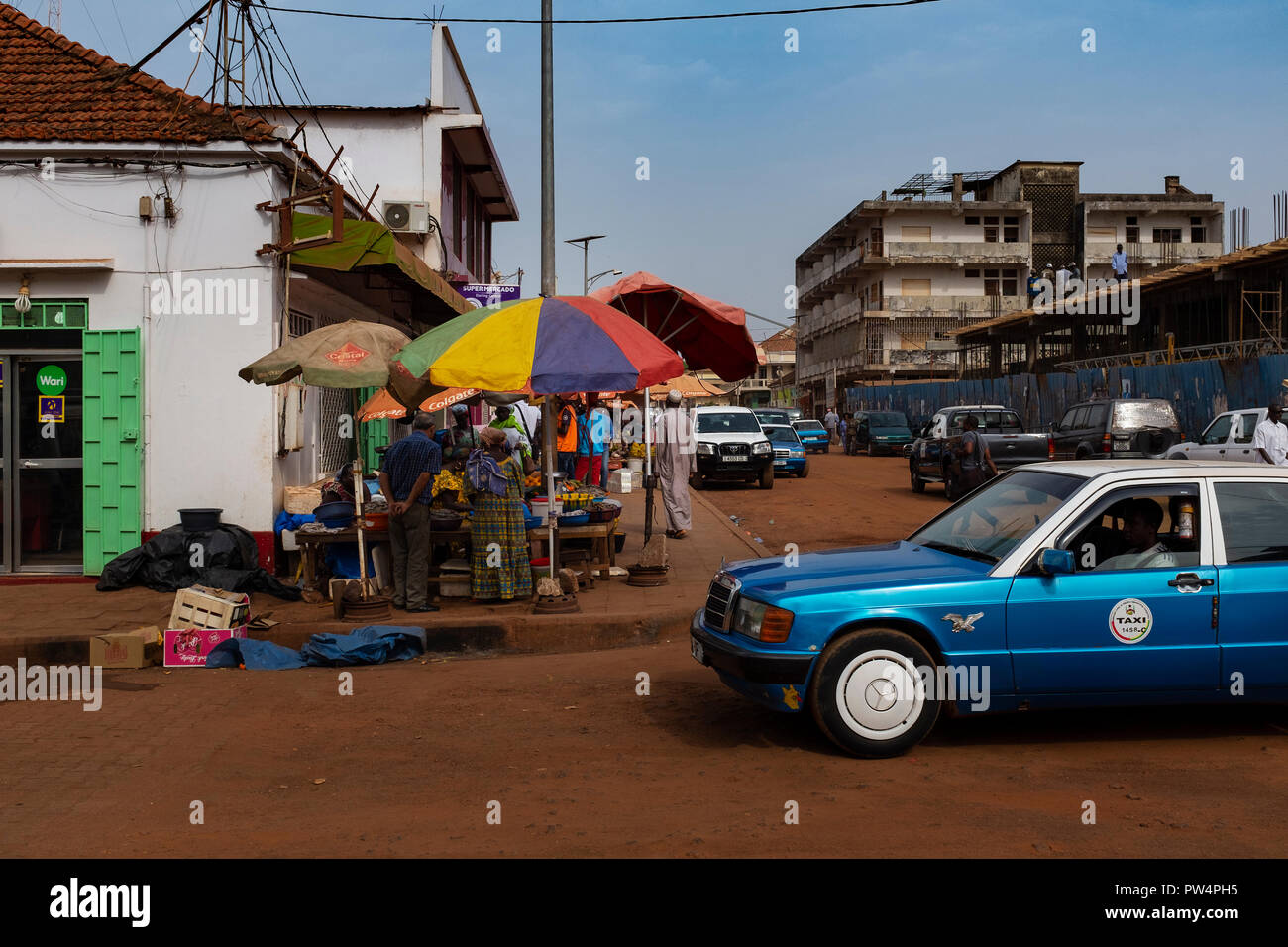 Bissau, Republic of Guinea-Bissau - February 5, 2018: Street scene in the city of Bissau with an old taxi and vendors, in Guinea-Bissau, West Africa Stock Photo