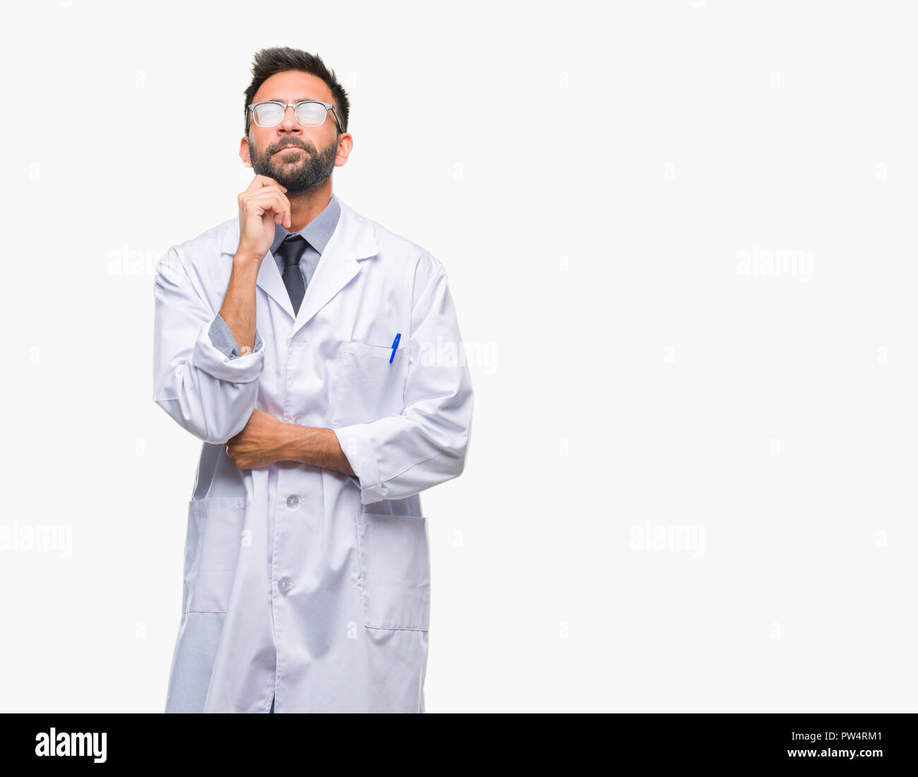 Adult hispanic scientist or doctor man wearing white coat over isolated background with hand on chin thinking about question, pensive expression. Smil Stock Photo