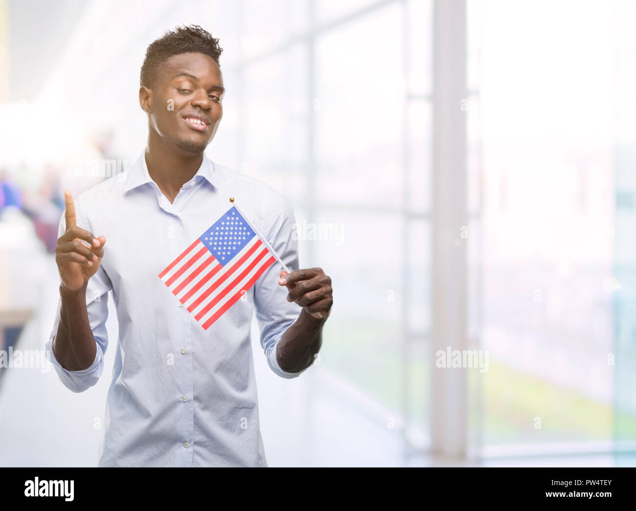 Young african american man holding USA flag surprised with an idea or ...