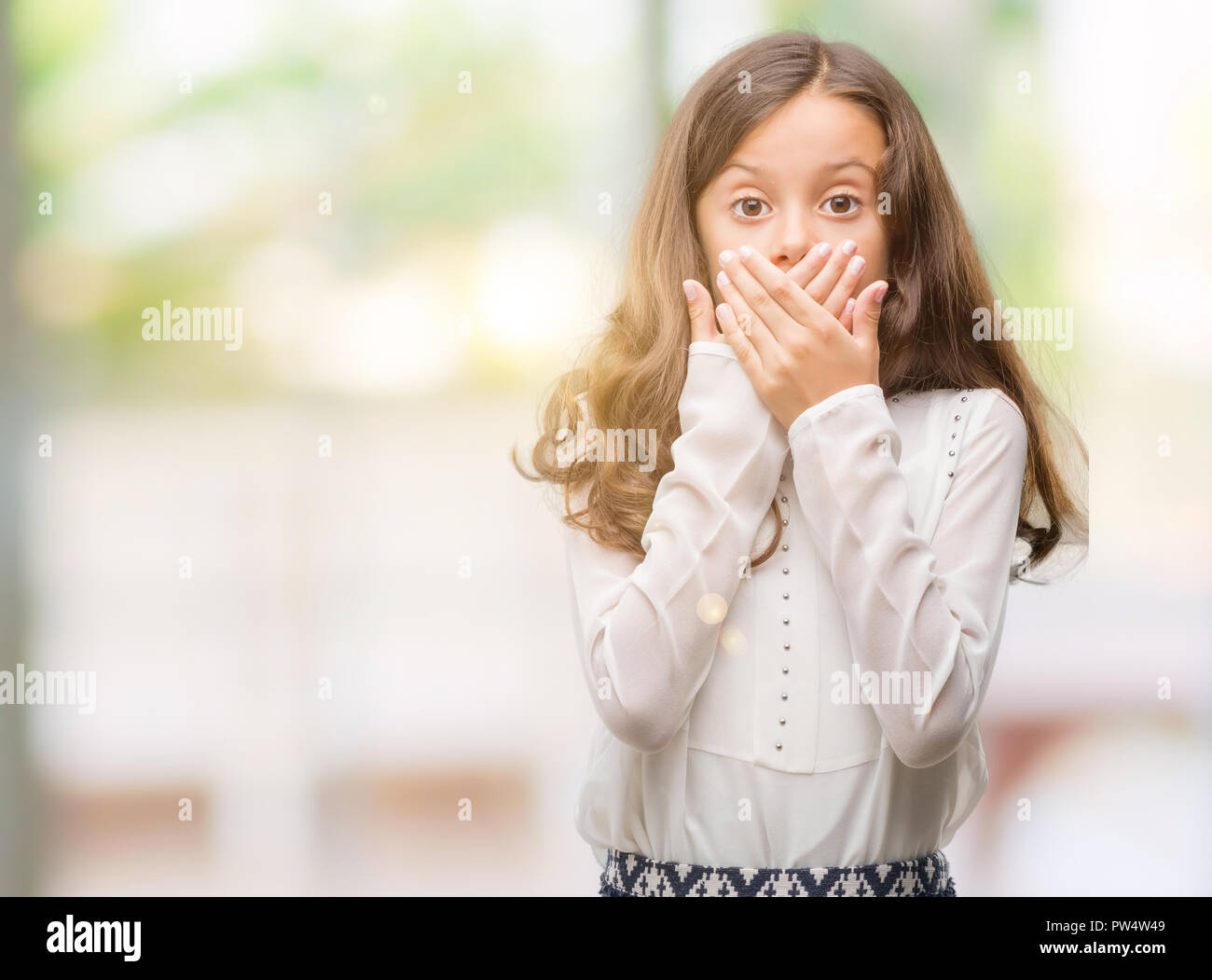 Brunette hispanic girl shocked covering mouth with hands for mistake. Secret concept. Stock Photo