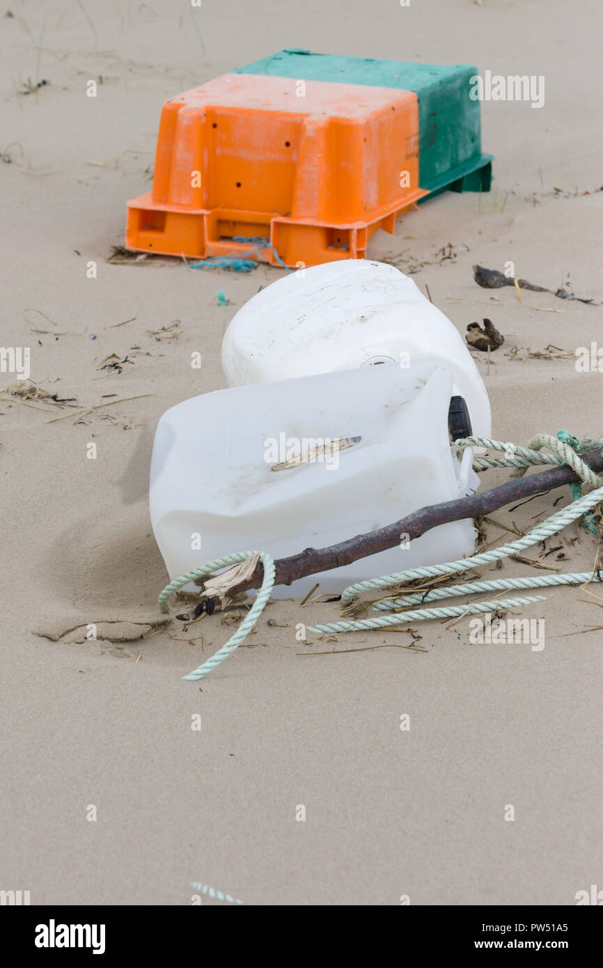 Plastic rubbish washed up on a beach and part buried in the sand an example of the many pieces of garbage in the oceans around the world Stock Photo