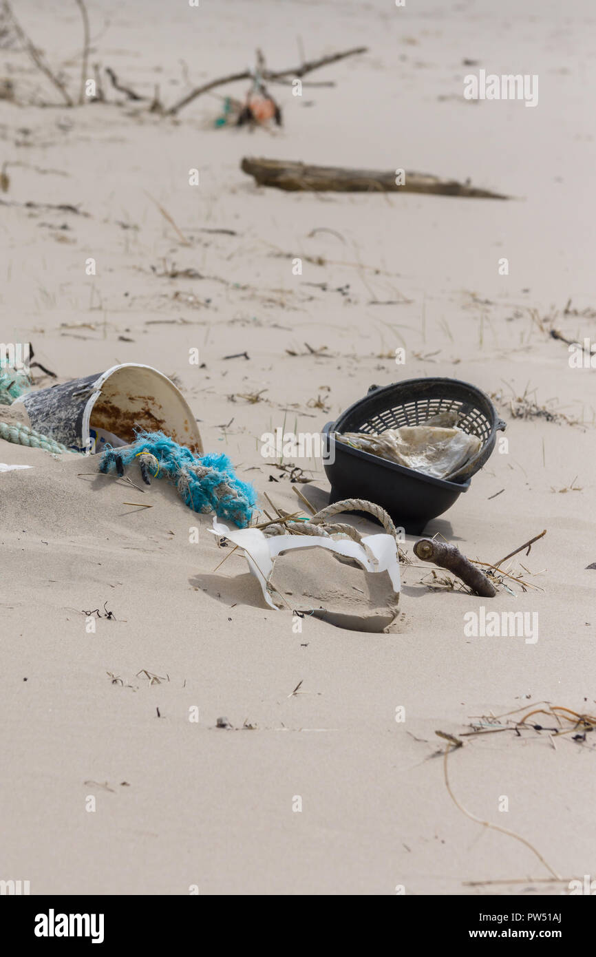 Plastic rubbish washed up on a beach and part buried in the sand an example of the many pieces of garbage in the oceans around the world Stock Photo