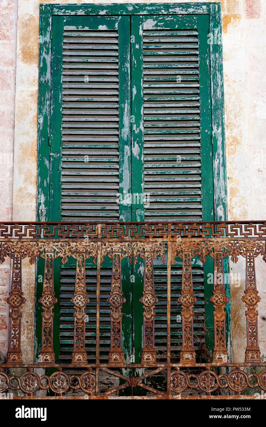 An old green shutter with rusty balcony in the Italian town of Ceglie in the Puglia region of southern Italy. Stock Photo