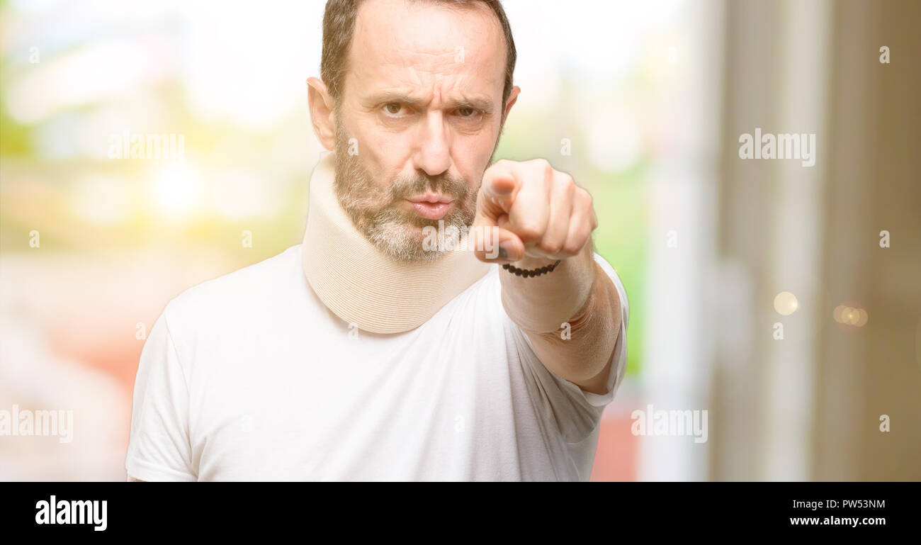 Injured senior man using a neck brace pointing to the front with finger