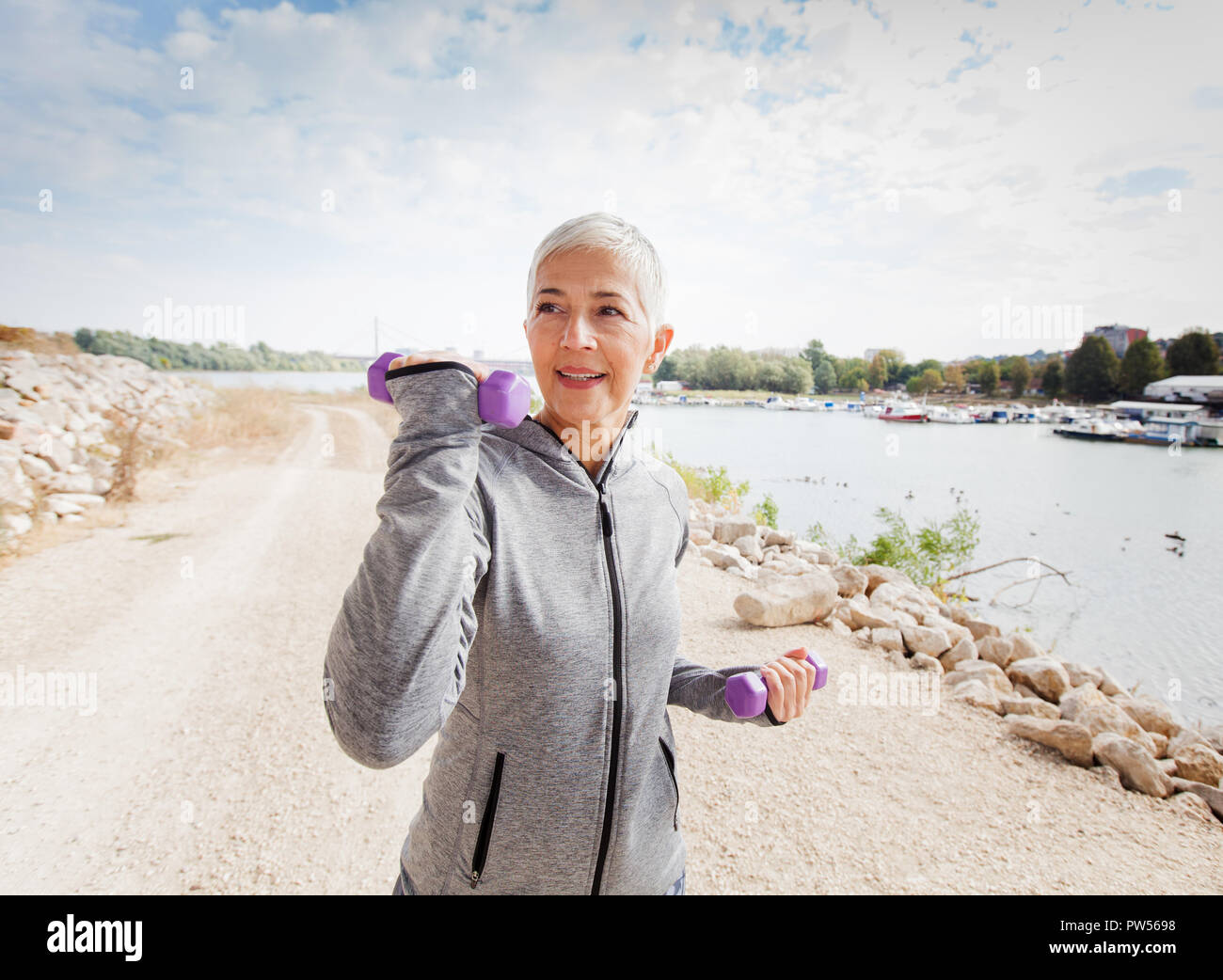 Healthy Middle Aged Woman In Sports Clothes Working With Weights Outdoor . Stock Photo