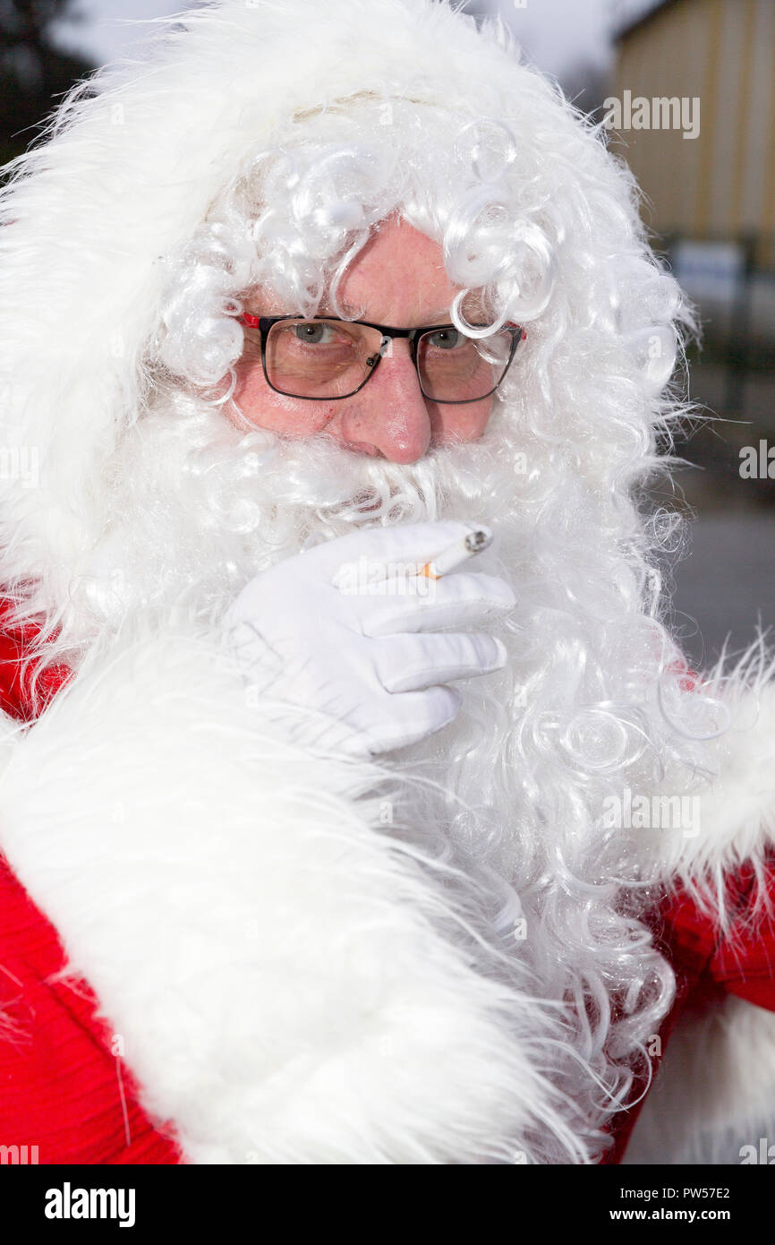 Portrait of funny Santa Claus looking at the camera while smokin a cigarette. Stock Photo