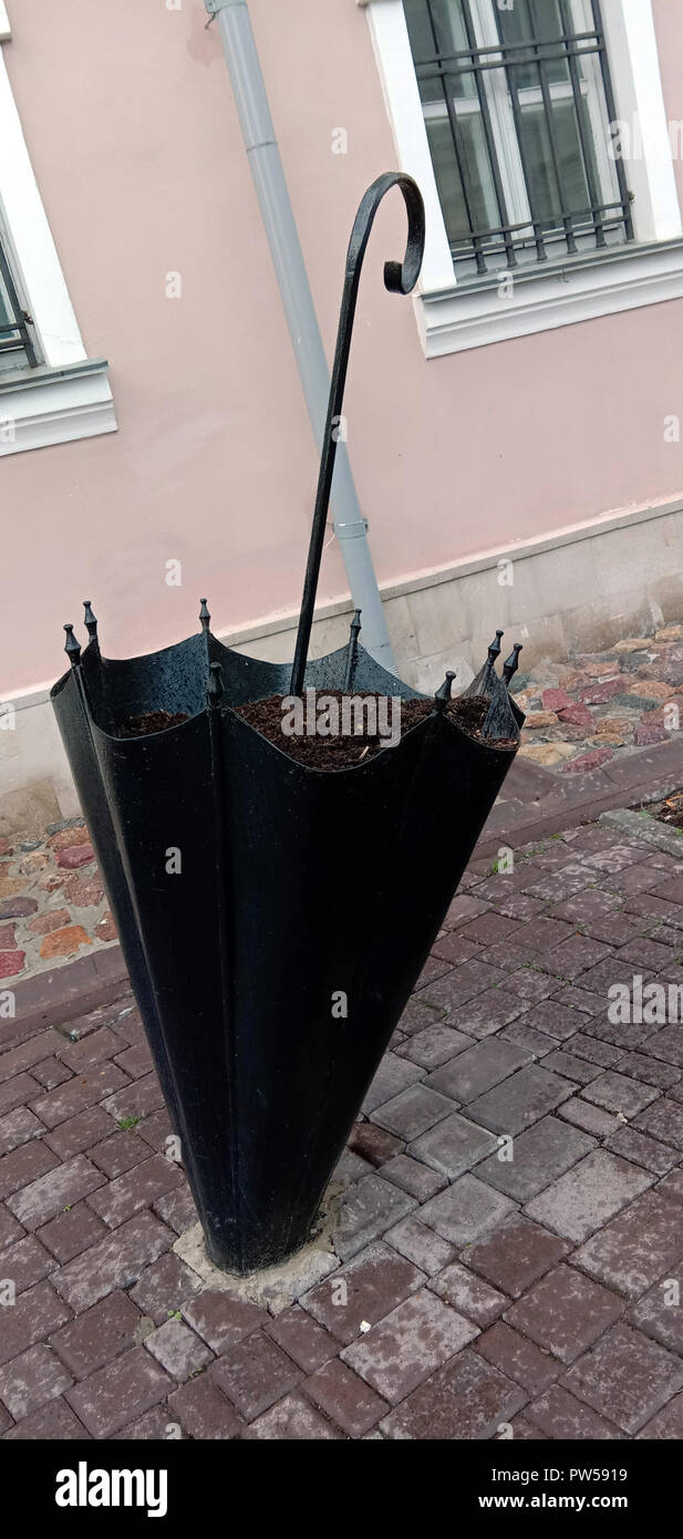 Original flower bed for flowers in the form of a stuck iron umbrella in the paving slabs. Russia. Stock Photo