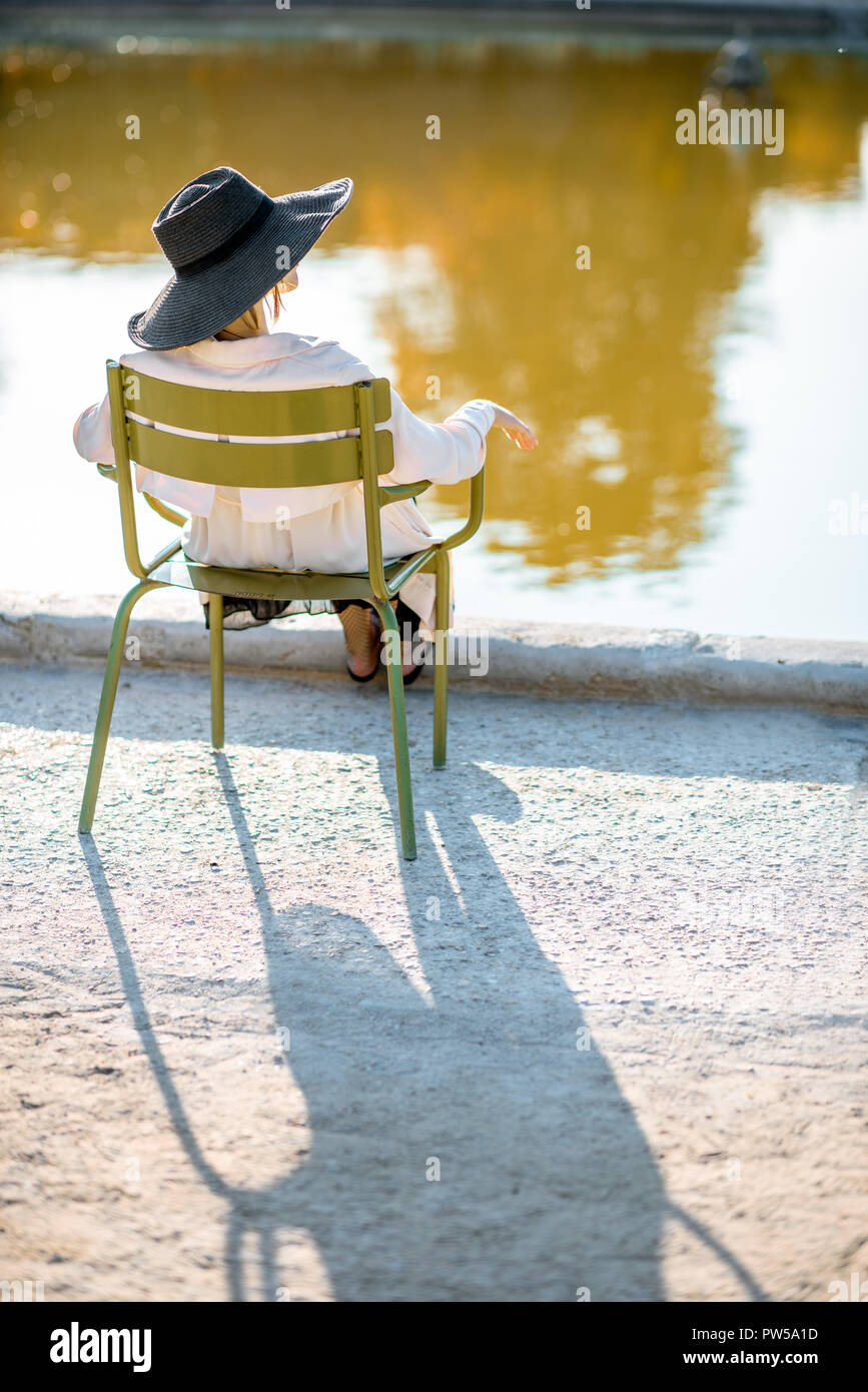 Woman In Hat Sitting Back On The Famous Green Chair Near The