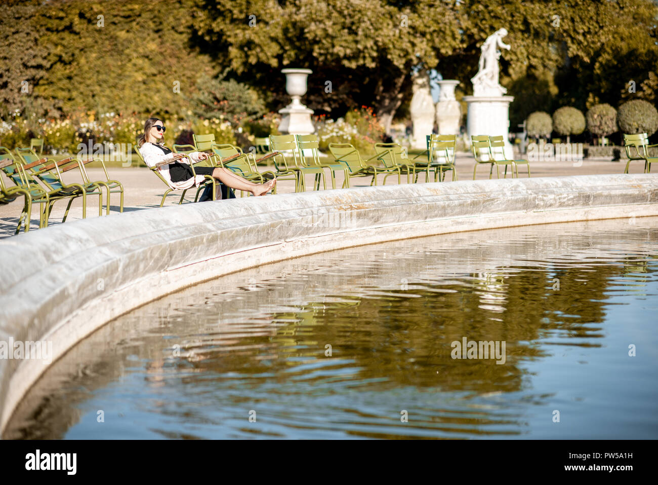 Woman Sitting On The Famous Green Chair Near The Fountain In