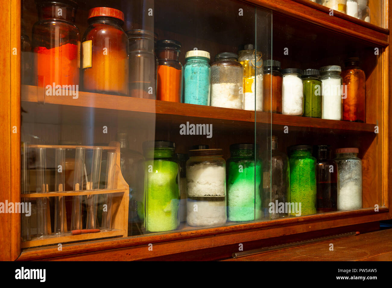 Glass jars full of colorful chemical elements on an old shelf. Stock Photo