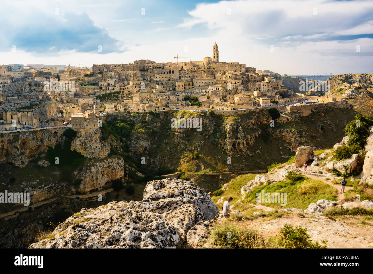 Matera; Italy - August 18; 2018: Tourists on the paths on the hill in front of the Sassi of Matera Stock Photo
