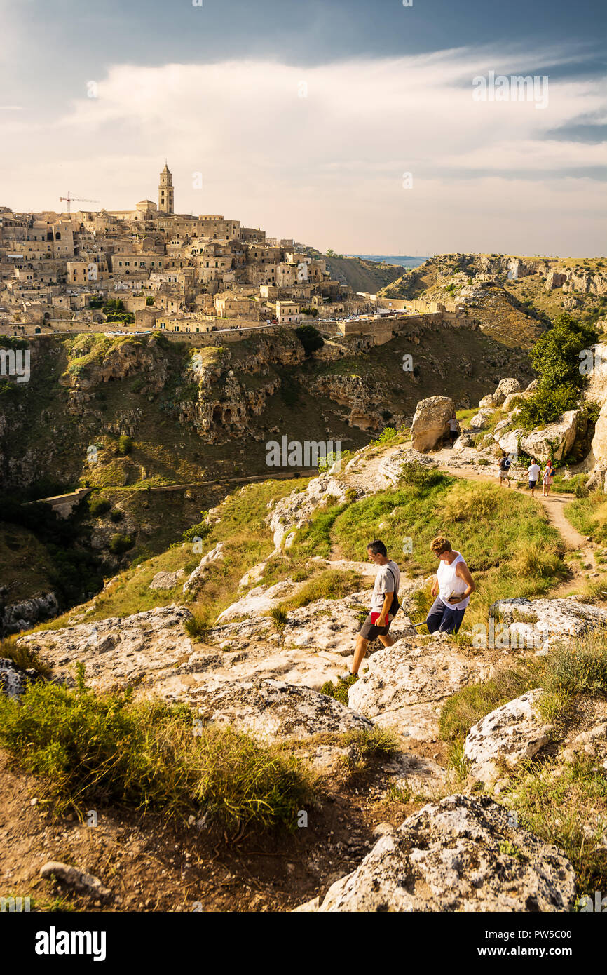 Matera, Italy - August 18, 2018: Tourists on the paths on the hill in front of the Sassi of Matera Stock Photo