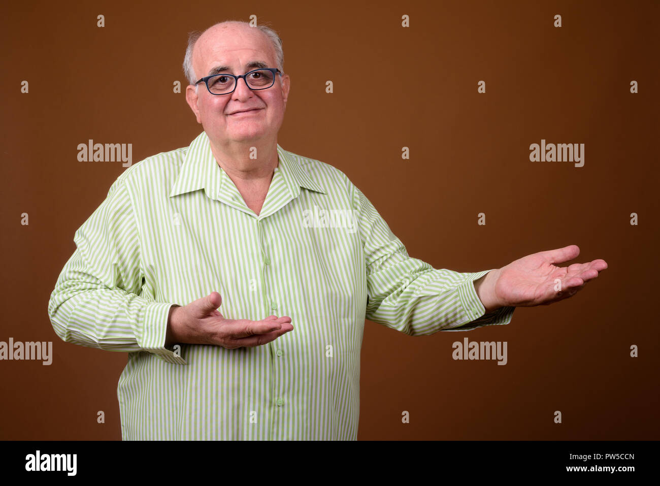 Overweight senior man wearing eyeglasses against brown backgroun Stock Photo