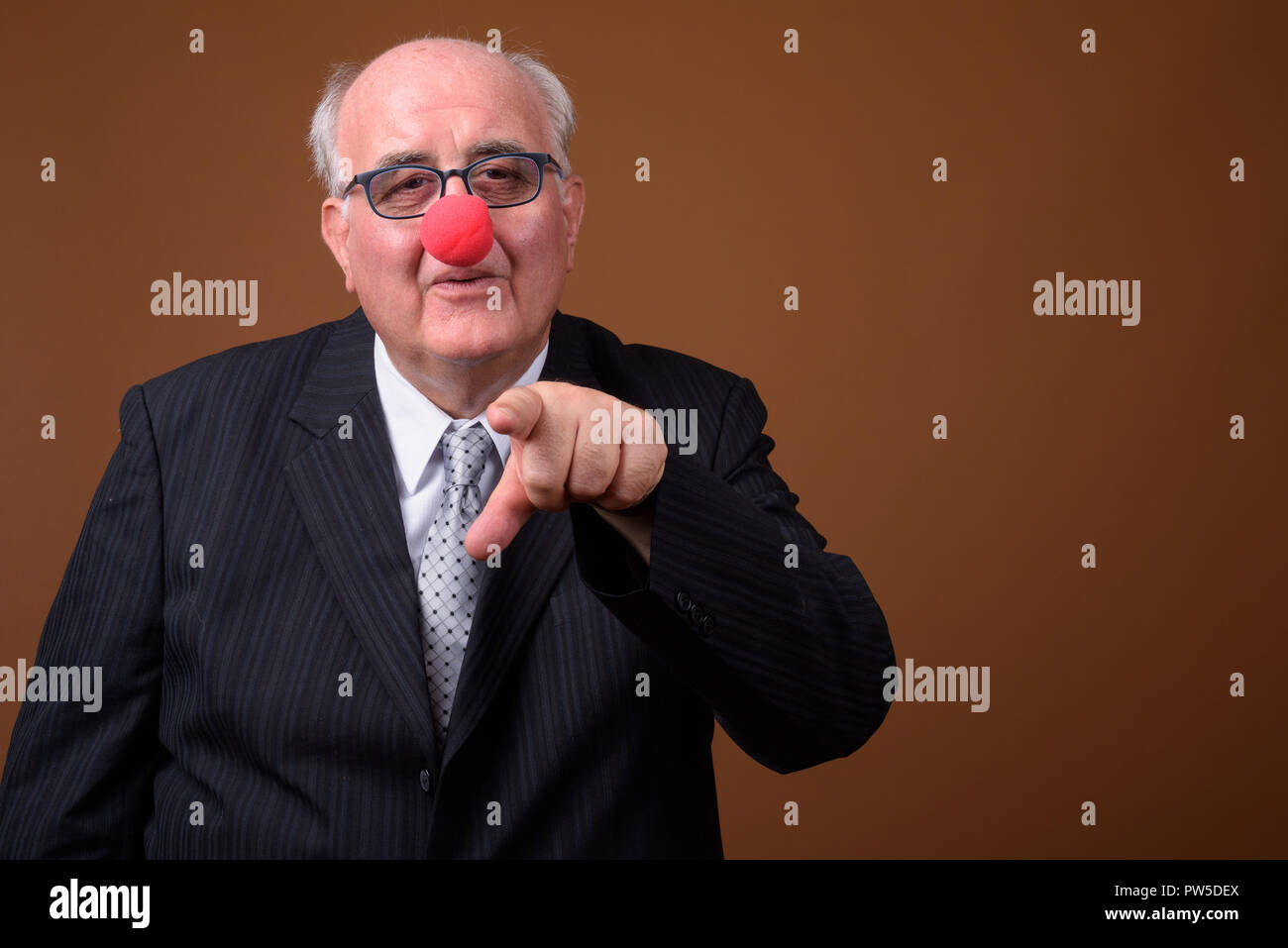 Overweight senior businessman wearing red clown nose Stock Photo