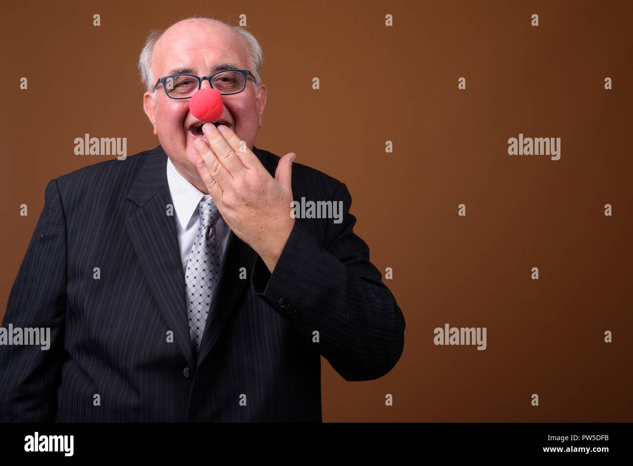 Overweight senior businessman wearing red clown nose Stock Photo