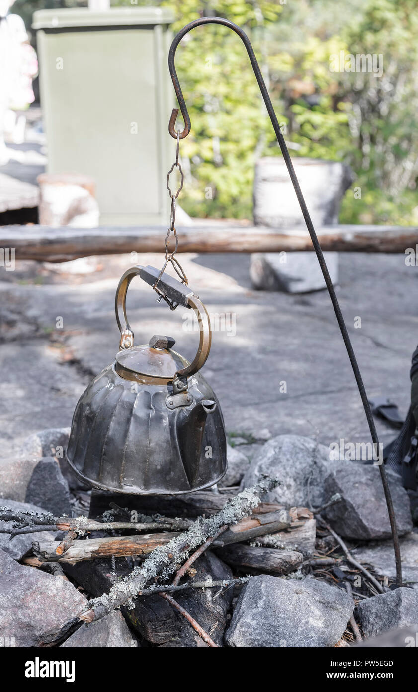 https://c8.alamy.com/comp/PW5EGD/metal-camp-kettle-hanging-over-the-coals-campfire-PW5EGD.jpg