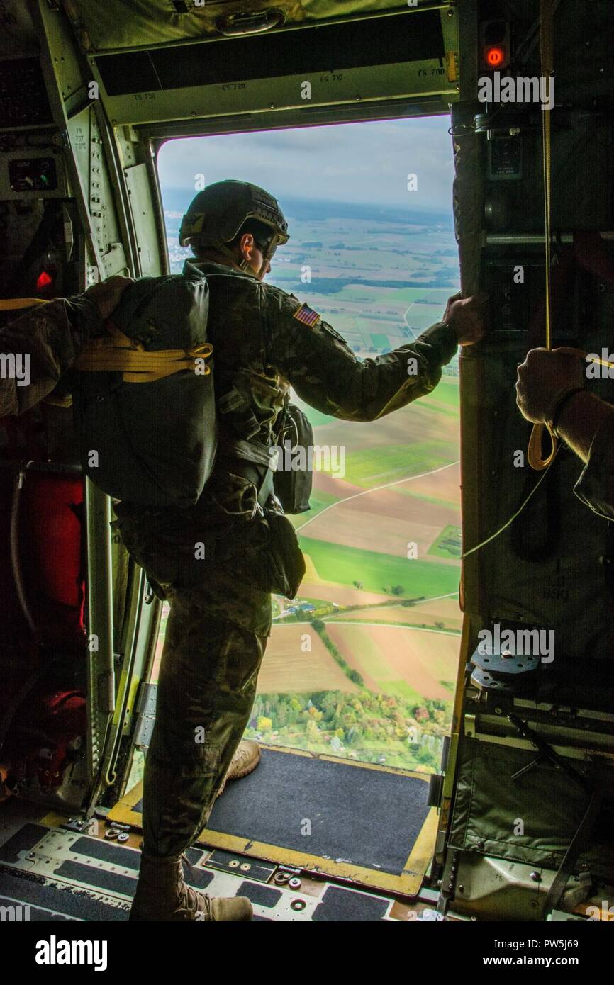 A Jumpmaster assigned to 1st Battalion, 10th Special Forces Group (Airborne), looks out the door of a C-130 Hercules for a reference point during an airborne operation near Stuttgart, Germany, Sept. 20th, 2017. Jumpmasters use reference points to ensure they are on the correct flight path and to help determine the distance to their drop zone. The jump demonstrated Group’s ability to lead airborne operations in the European theater. Airborne insertions are one of the many infiltration platforms available to Special Operations when responding to a crisis. Stock Photo