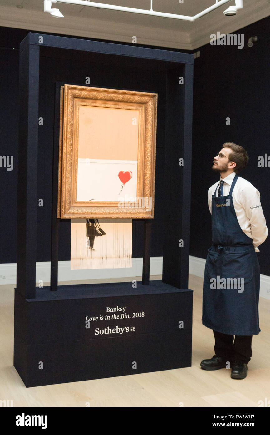 London, UK. 12th Oct, 2018. A staff member of Sotheby's presents Banksy's 'Love is in the Bin' in London, Britain on Oct. 12, 2018. Originally titled 'Girl with Balloon', the British street artist Banksy made his painting self-destruct on Oct. 5 moments after it was auctioned for 1.042 million British pounds (1.37 million U.S. dollars) at Sotheby's in London. Credit: Ray Tang/Xinhua/Alamy Live News Stock Photo
