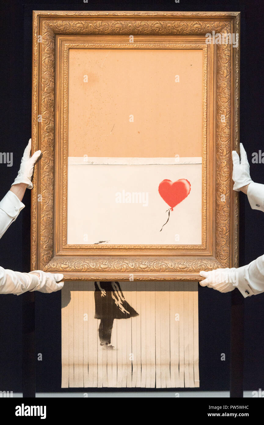 London, UK. 12th Oct, 2018. Sotheby's staff members present Banksy's 'Love is in the Bin' in London, Britain on Oct. 12, 2018. Originally titled 'Girl with Balloon', the British street artist Banksy made his painting self-destruct on Oct. 5 moments after it was auctioned for 1.042 million British pounds (1.37 million U.S. dollars) at Sotheby's in London. Credit: Ray Tang/Xinhua/Alamy Live News Stock Photo