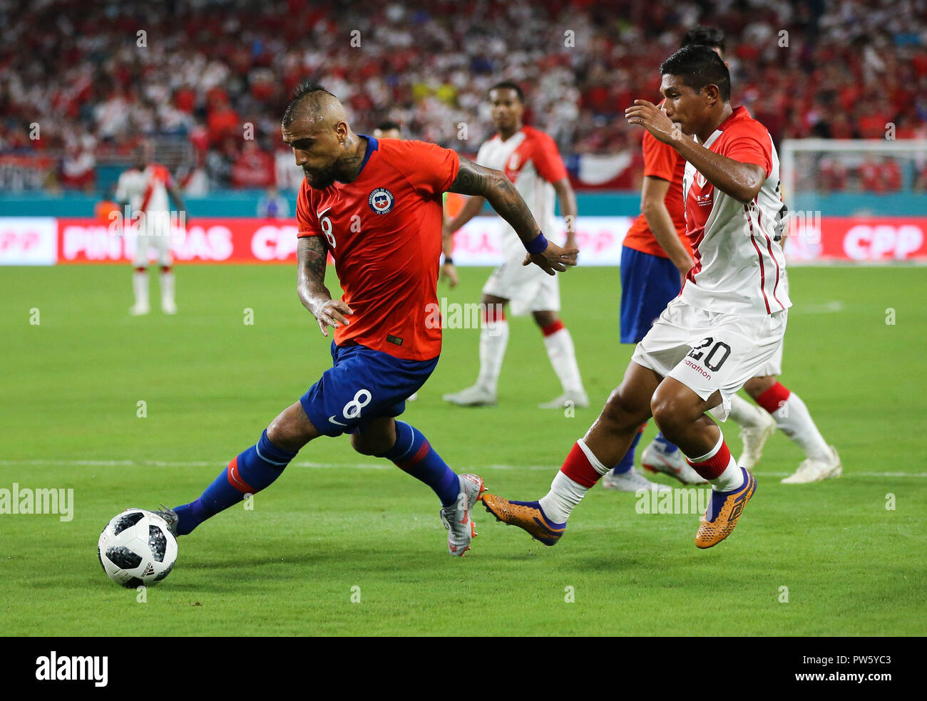 Miami Gardens, Florida, USA. 12th Oct, 2018. Chile midfielder ARTURO VIDAL (8) moves the ball past Peru midfielder EDISON FLORES (20) during an international friendly match between the Peru and Chile national soccer teams, at the Hard Rock Stadium in Miami Gardens, Florida. Credit: Mario Houben/ZUMA Wire/Alamy Live News Stock Photo