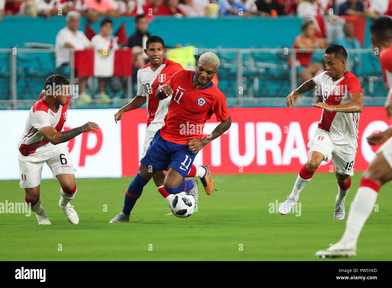 Miami Gardens, Florida, USA. 12th Oct, 2018. Chile forward JUNIOR FERNANDES (11) moves the ball, challenged by Peru defender MIGUEL TRAUCO (6), midfielder EDISON FLORES (20), and midfielder VICTOR YOTUN (19), during an international friendly match between the Peru and Chile national soccer teams, at the Hard Rock Stadium in Miami Gardens, Florida. Credit: Mario Houben/ZUMA Wire/Alamy Live News Stock Photo