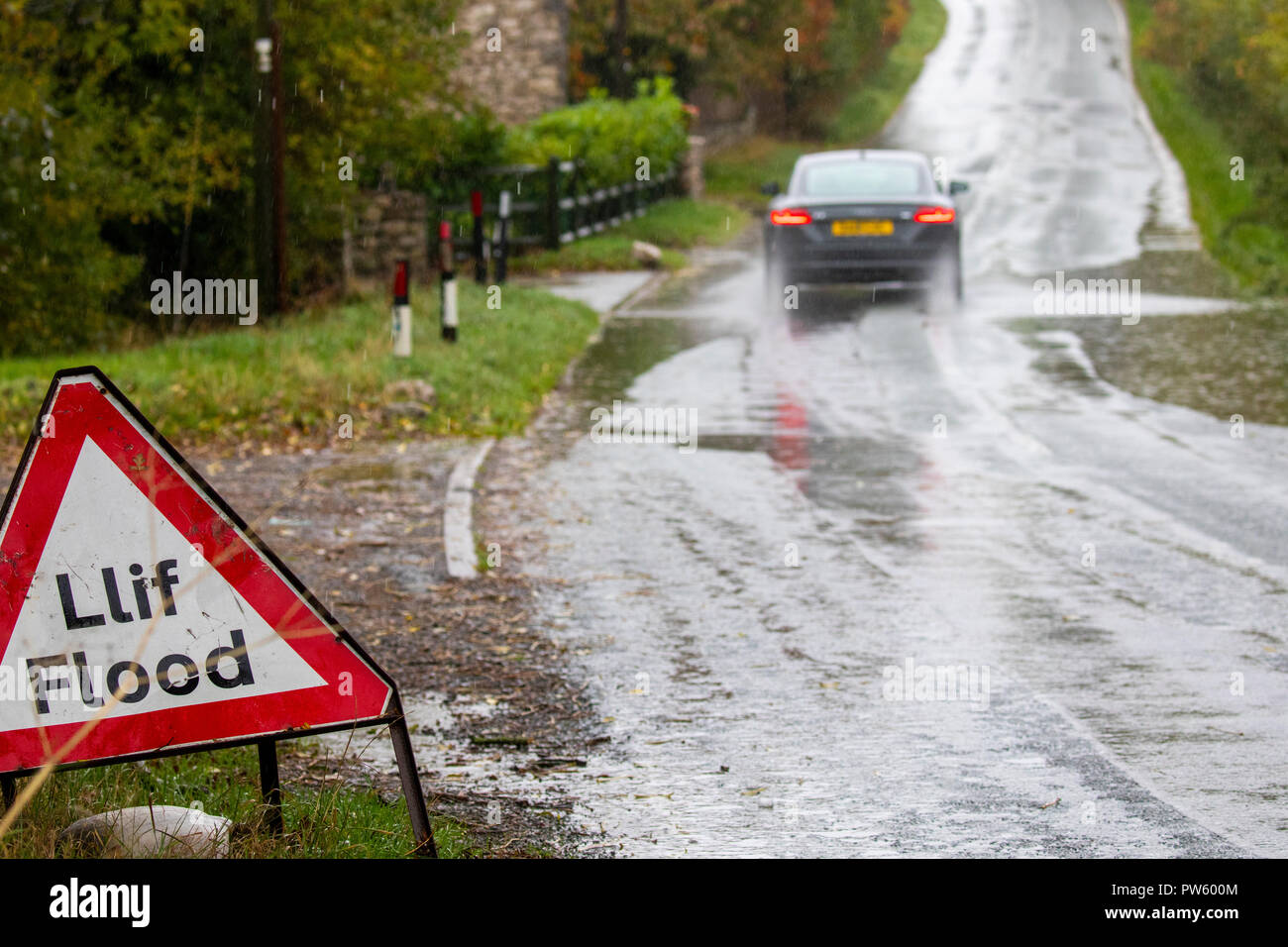 Flintshire, North Wales, 13th October 2018. UK Weather: Heavy rain for most today with weather warnings in place and flood warnings for parts of Wales. Heavy rain and flooding along rural roads near to the village of Lixwm, Flintshire as a car drives cautiously through flood water © DGDImages/AlamyNews Stock Photo