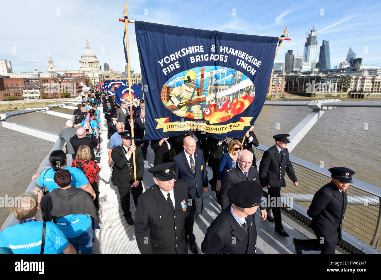 London, UK.  13 October 2018.  After a formal wreath-laying ceremony at the National Firefighters’ Memorial next to St Paul’s Cathedral, in memory of fallen firefighters representing every fire service in the UK, members of the Fire Brigades Union (FBU) take part in a formal procession across the Millennium Bridge followed by a service at Southwark Cathedral to commemorate the centenary of the formation of the FBU. The activities are the largest ever ceremonial event for firefighters killed in the line of duty.  Credit: Stephen Chung / Alamy Live News Stock Photo