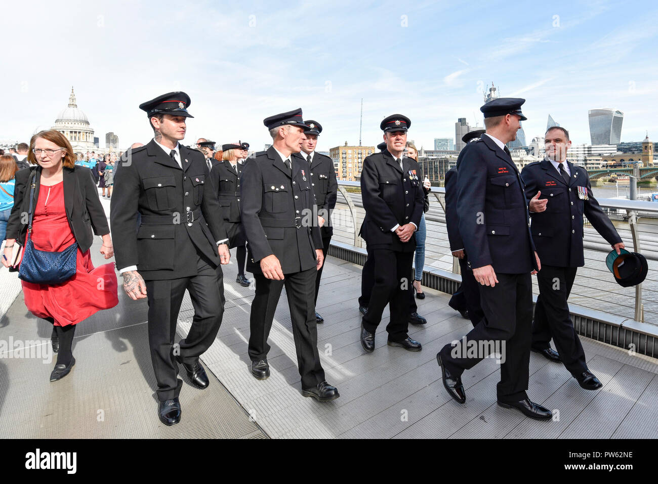 London, UK.  13 October 2018.  After a formal wreath-laying ceremony at the National Firefighters’ Memorial next to St Paul’s Cathedral, in memory of fallen firefighters representing every fire service in the UK, members of the Fire Brigades Union (FBU) take part in a formal procession across the Millennium Bridge followed by a service at Southwark Cathedral to commemorate the centenary of the formation of the FBU. The activities are the largest ever ceremonial event for firefighters killed in the line of duty.  Credit: Stephen Chung / Alamy Live News Stock Photo