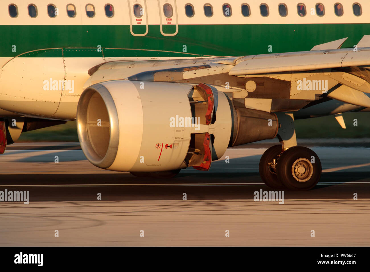 Closeup of a CFM56 turbofan jet engine on an Airbus A320 airliner while landing with thrust reversers activated. Left main wheels also visible. Stock Photo