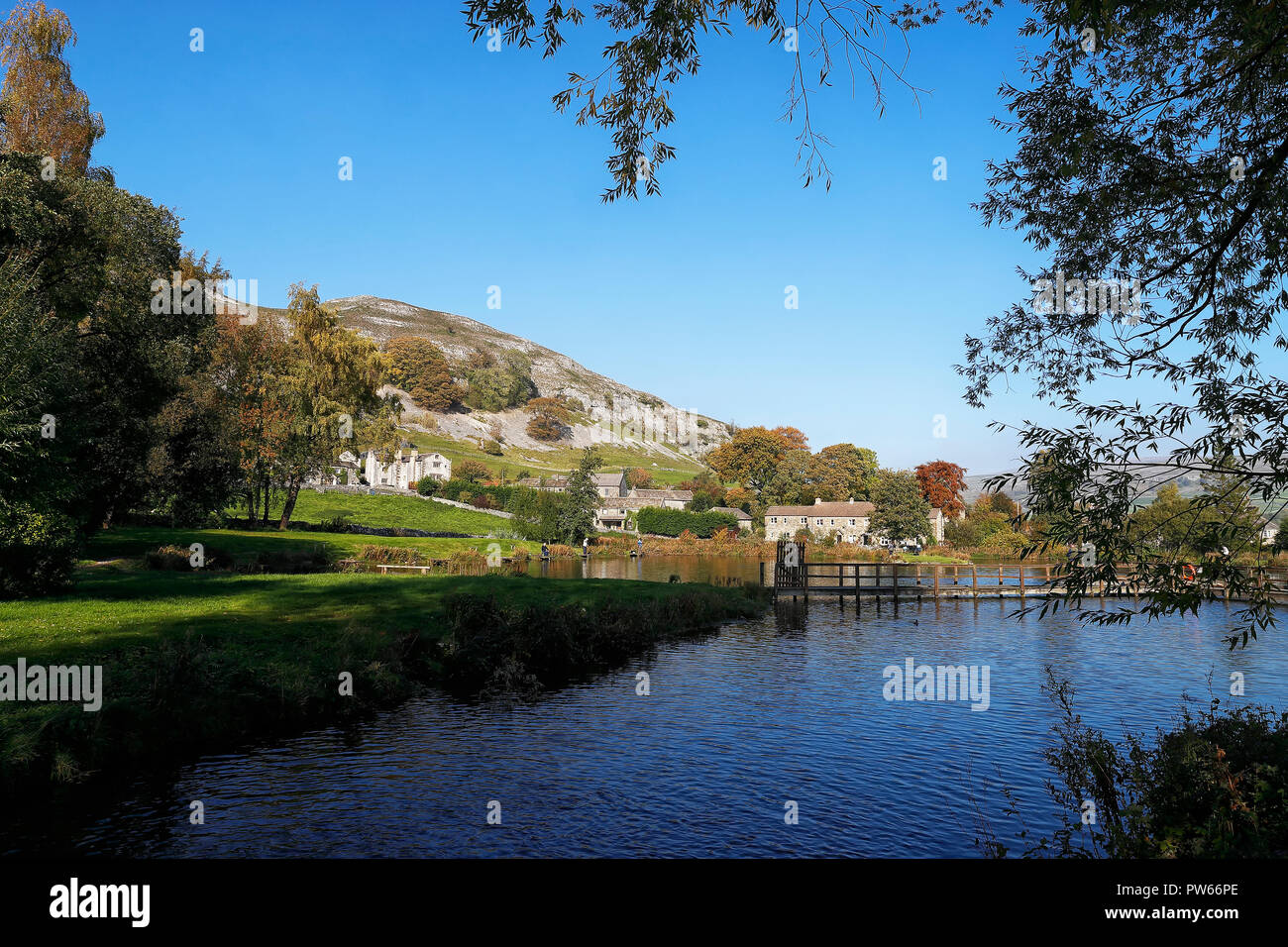 Kilnsey Trout farm fishing lakes with the village in the background with the Crag rising above Stock Photo