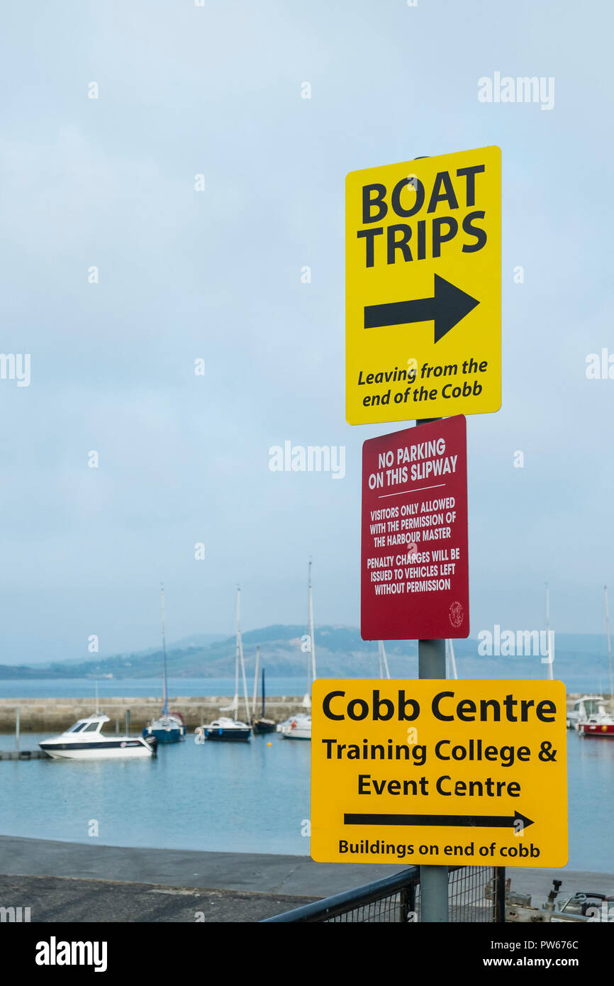 A signpost with information signs at Lyme Harbour in the coastal town of Lyme Regis in Dorset