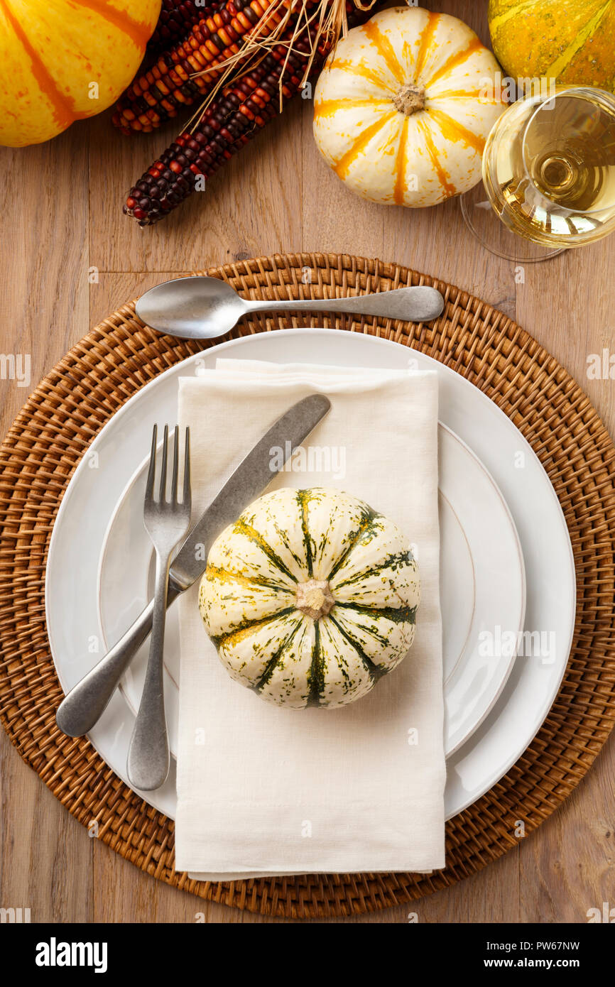 Festive Fall Thanksgiving table setting place setting home decorations with white china plates dishes, silverware fork and spoon, linen cloth napkin,  Stock Photo
