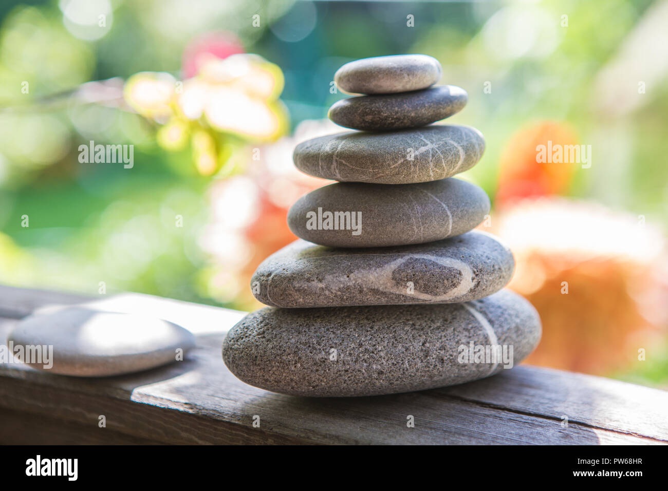 Balance of pebbles against the background of a flowering garden Stock Photo