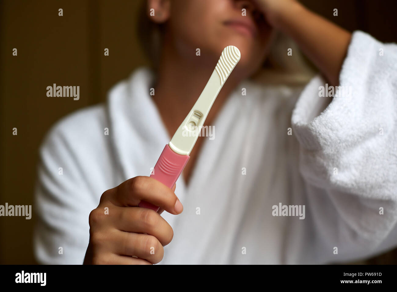 Concerned Woman In Bathroom Using Home Pregnancy Test Stock Photo