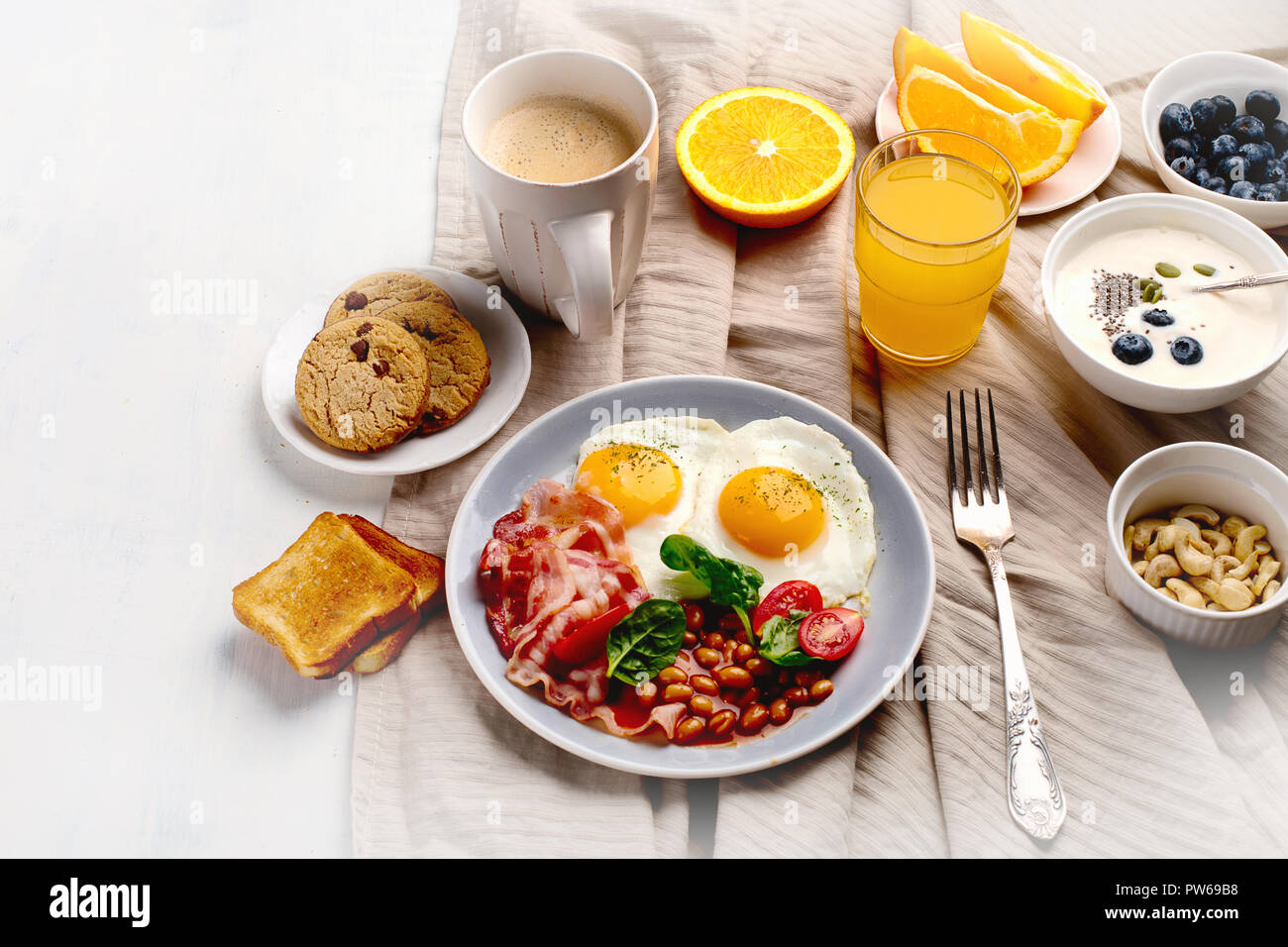 Breakfast with fried eggs, bacon, orange juice, yogurt and toasts Stock
